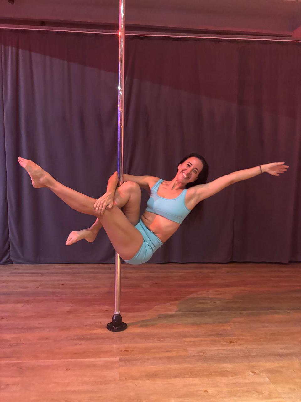 Aluna sorrindo durante aula de pole dance