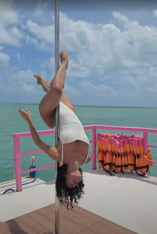 Aluna invertida na barra com o mar ao fundo